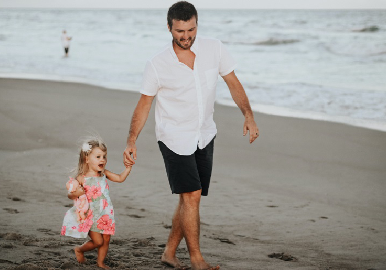 a father and daughter walking at the beach